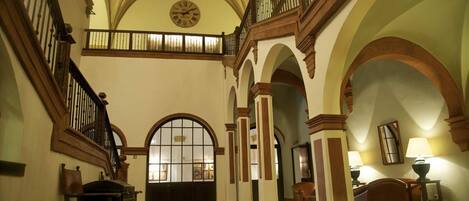 A spacious interior with high ceilings, arched doorways, and a grand staircase.