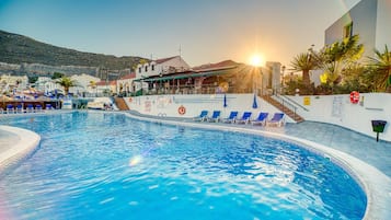 Una piscina al aire libre, tumbonas