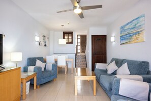 A modern living room with a sofa, chairs, a coffee table, and a dining area with a table and chairs. - Ona Las Rosas (Santiago del Teide)