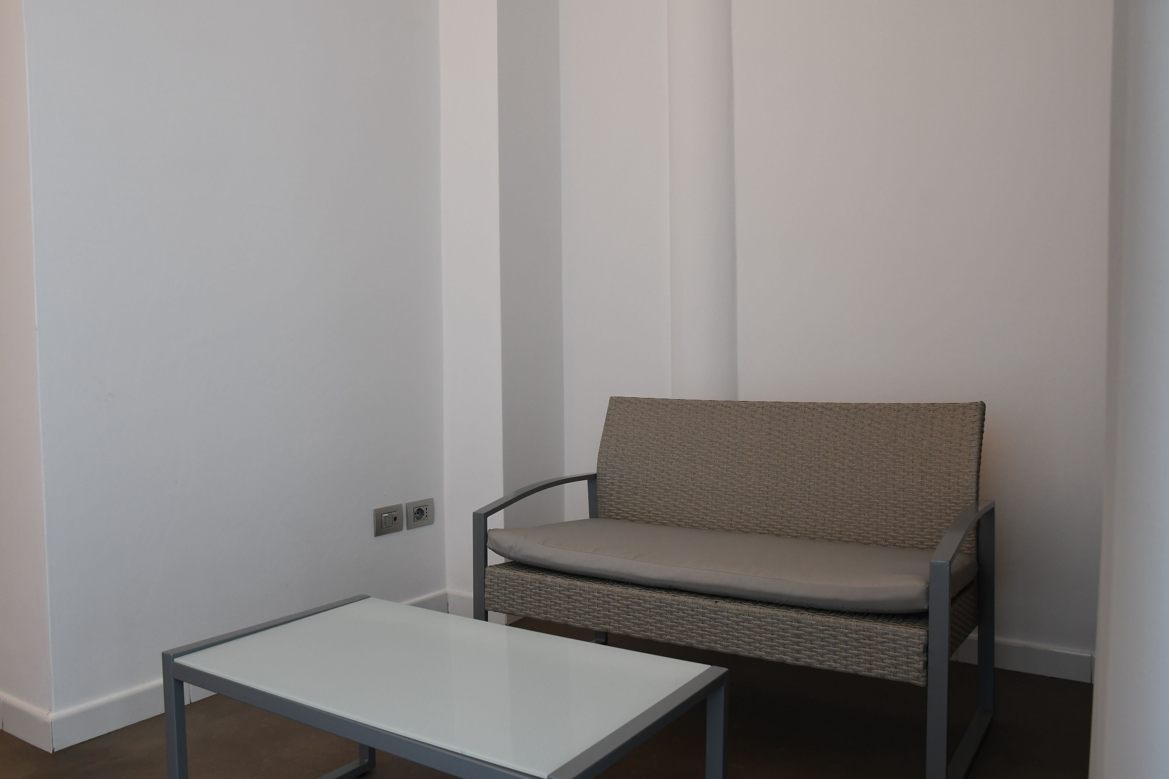 A small room with a white table and a wicker chair.