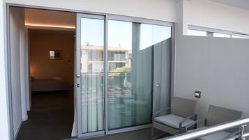 Ein modernes Hotelzimmer mit Balkon, einem Bett und einer Sitzecke mit Stühlen.