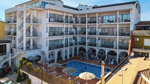 Un hôtel à plusieurs étages doté d’une piscine sur le toit, d’un espace extérieur aménagé et de balcons.