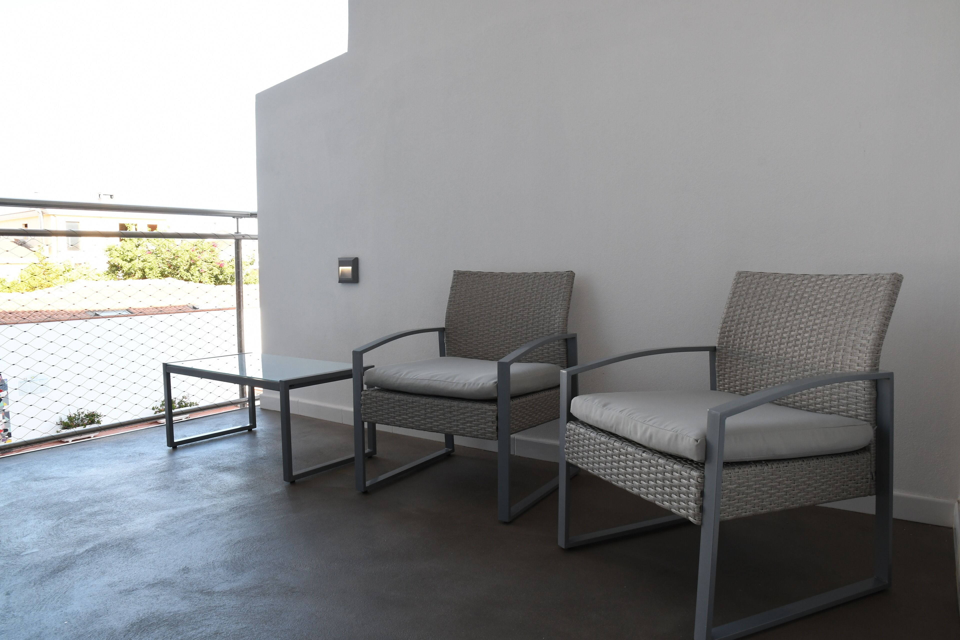 A modern room with two grey wicker chairs and a small metal table.