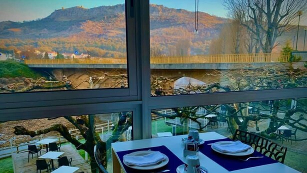 A dining area with a table set for two, overlooking a mountainous landscape. - Sever Rio Hotel (Marvao)