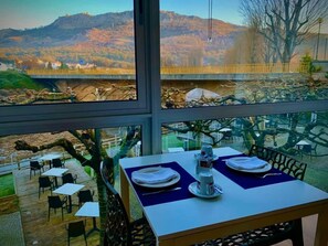 A dining area with a table set for two, overlooking a mountainous landscape. - Sever Rio Hotel (Marvao)