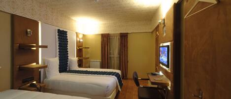 A hotel room with two beds, a desk with a computer, and a TV.