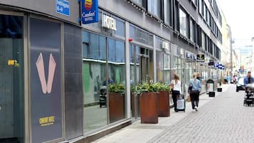 Ett Comfort Hotel med stora fönster, en tydlig fotavtryckssymbol och en skylt som anger åldersgruppen 65–49 år.