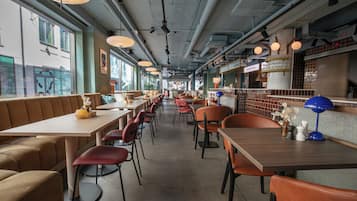 Un interior de restaurante con mesas comunes largas, cabinas y una zona de bar.