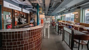 Una cafetería con mostrador, zona de estar y un desfibrilador externo automático visible.