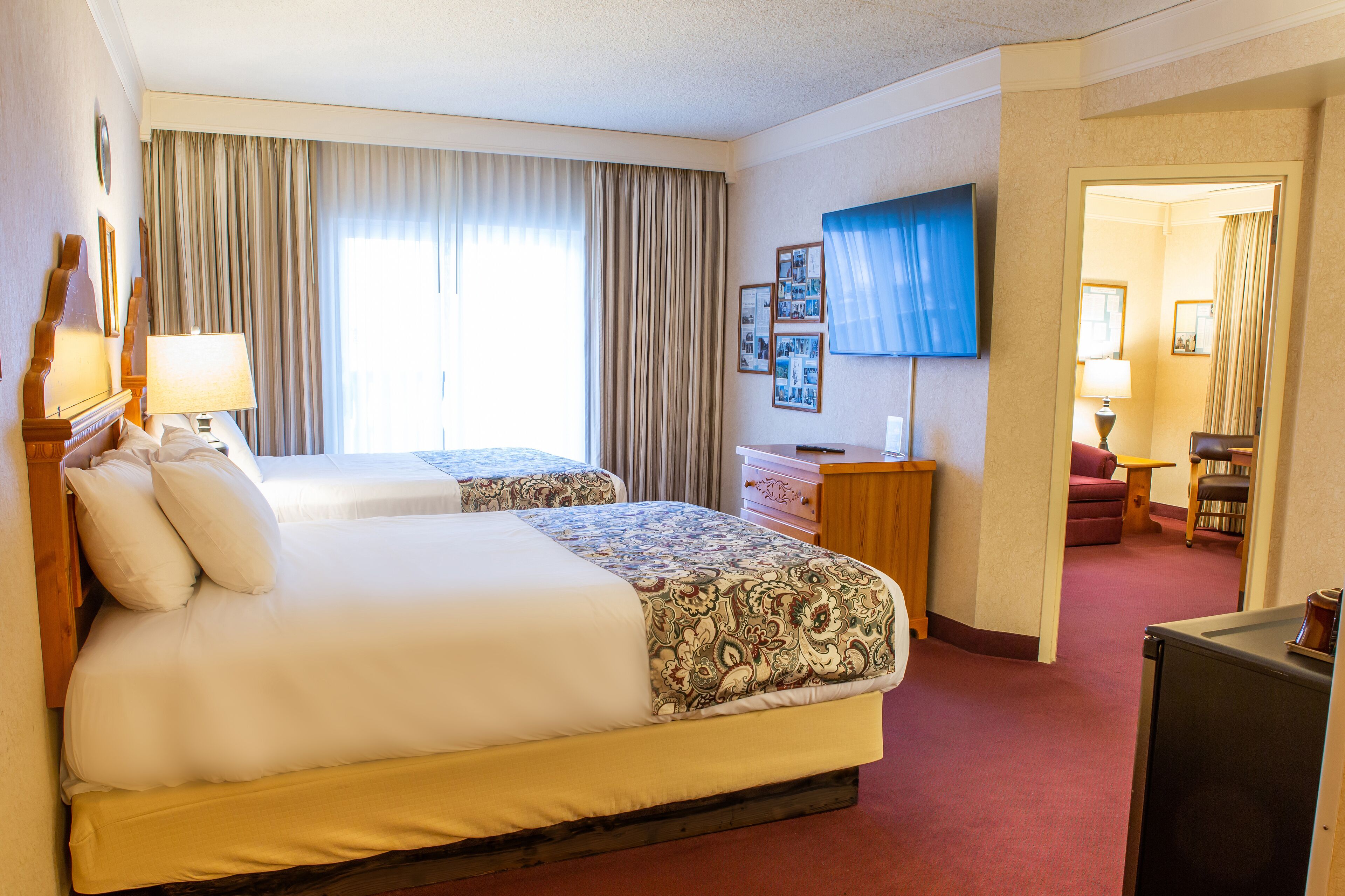A hotel room with two beds, a TV, a desk, and a chair.