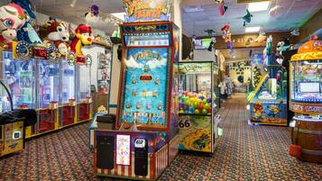 A brightly lit arcade with various gaming machines, including a 'Fish Bowl Frenzy' game, and a 'No Smoking Area' sign.
