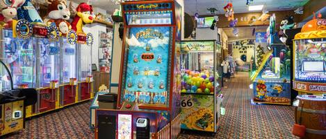 Une salle d’arcade bien éclairée, avec différents jeux, dont un jeu intitulé « Fish Bowl Frenzy », et un panneau indiquant « Zone non-fumeurs ».