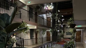 Atrio a più livelli con balconi, piante in vaso e uno spazio aperto centrale.