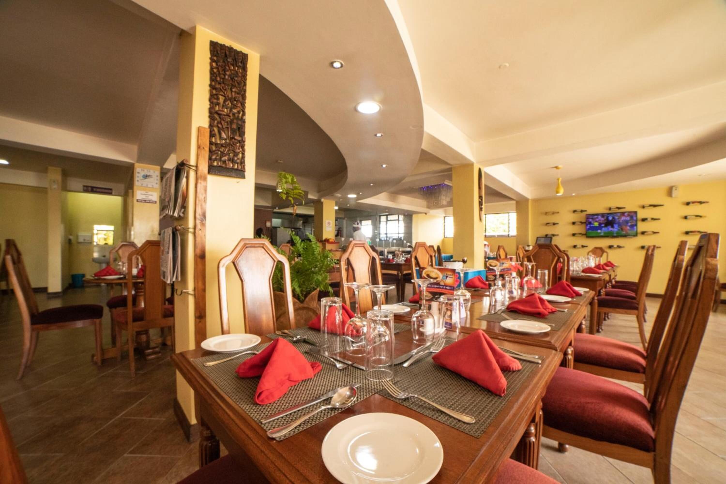 A dining area with a long wooden table set for a meal, surrounded by wooden chairs.