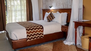 Un letto rifatto con cura, con una coperta a motivi a zig-zag marrone e bianca, una testiera in legno e un comodino con una lampada.