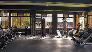 Una palestra con diverse attrezzature per esercizi, ampie finestre e vista sull'esterno.