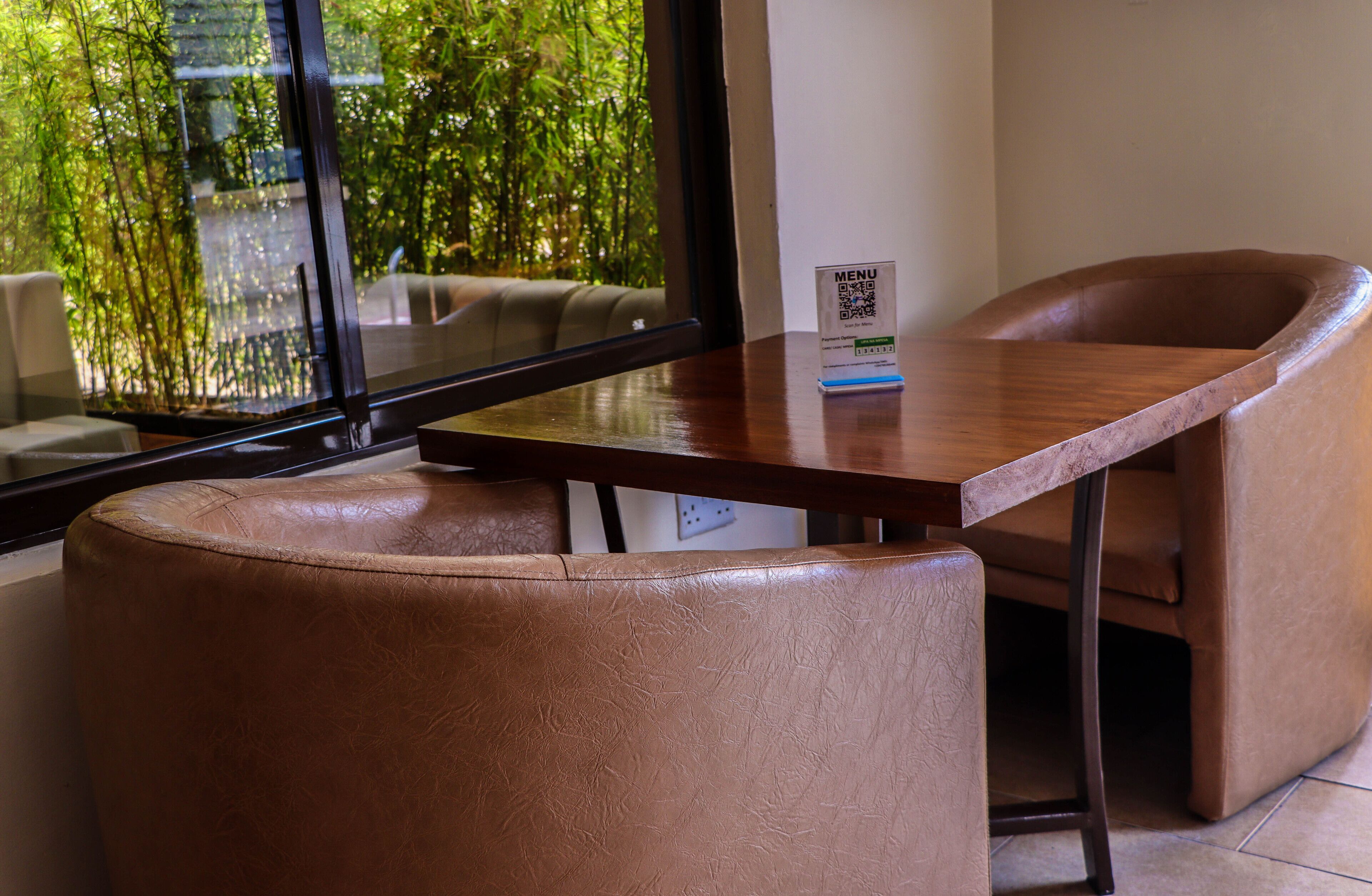 A modern room with a wooden table, a brown leather chair, and a window with a view of greenery.