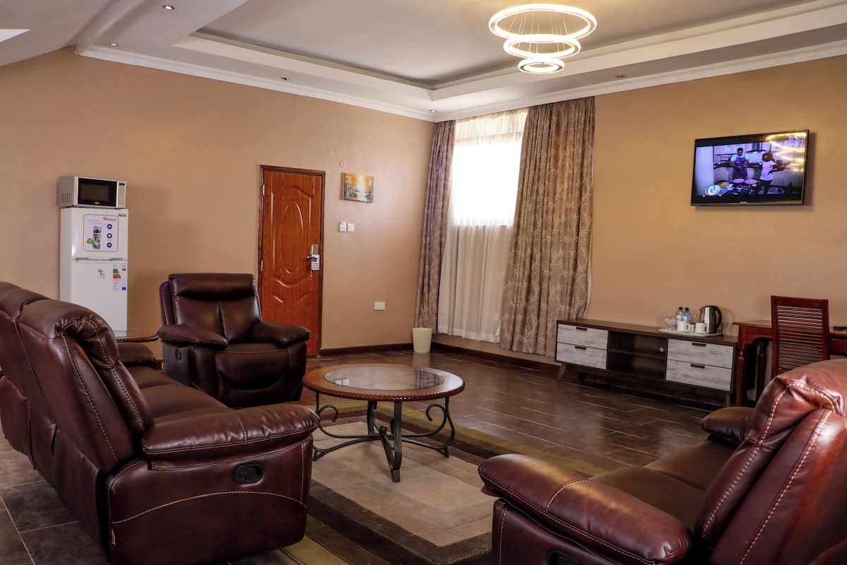 A living room with leather recliners, a glass coffee table, a flat-screen TV, a microwave, and a wooden door.