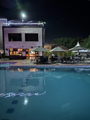 Een buitenzwembad, ligstoelen bij het zwembad