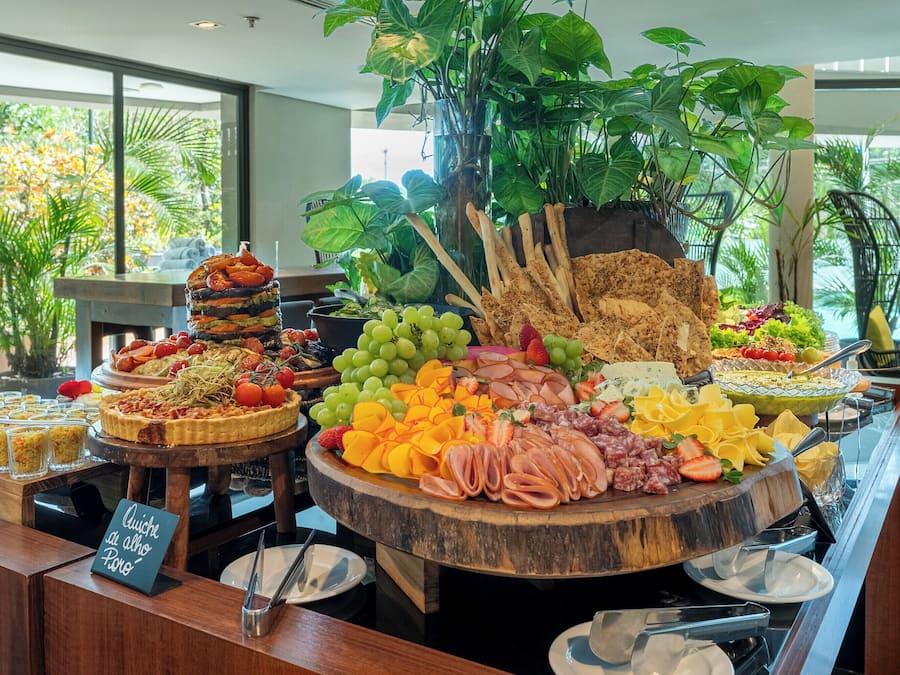 Un bufé con diversas opciones de comida, incluyendo frutas, quesos y embutidos.