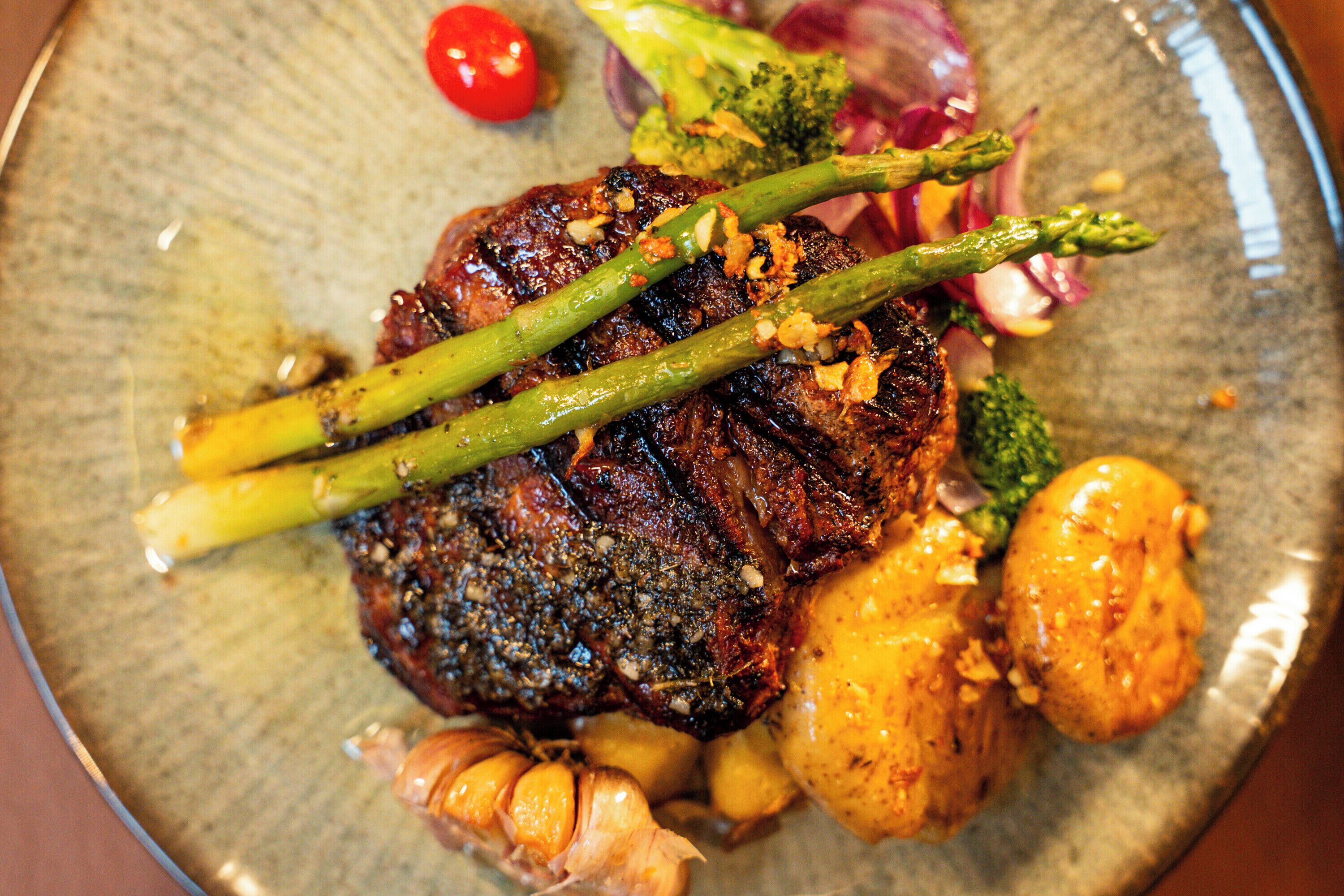 A steak with asparagus and roasted potatoes on a plate.