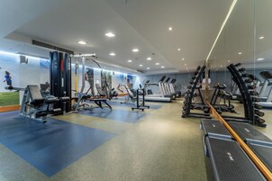 A gym with various exercise equipment, including treadmills, weight machines, and free weights.