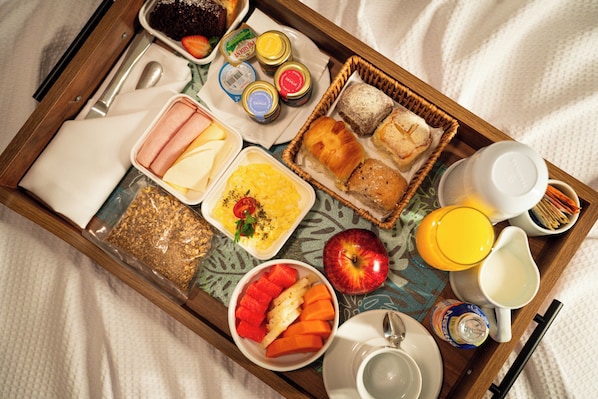 A breakfast tray with various food items, including bread, fruit, and condiments. - Hotel Deville Prime Campo Grande (Campo Grande)