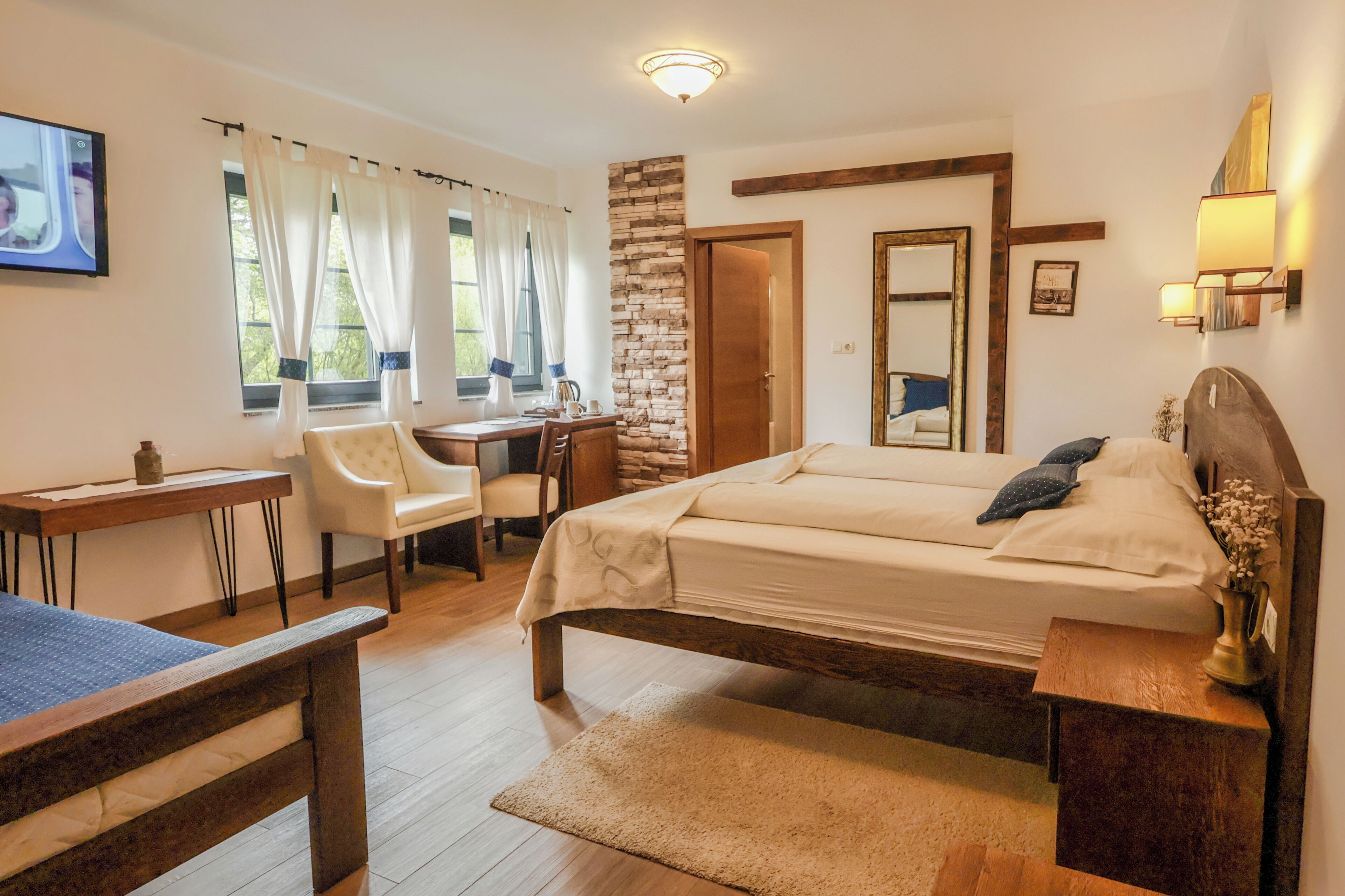 A bedroom with a bed, desk, chair, and a small table.