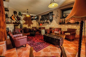 A cozy lounge area with leather sofas, a patterned rug, and a stone wall backdrop. - Plitvice Luxury (Plitvicka Jezera)