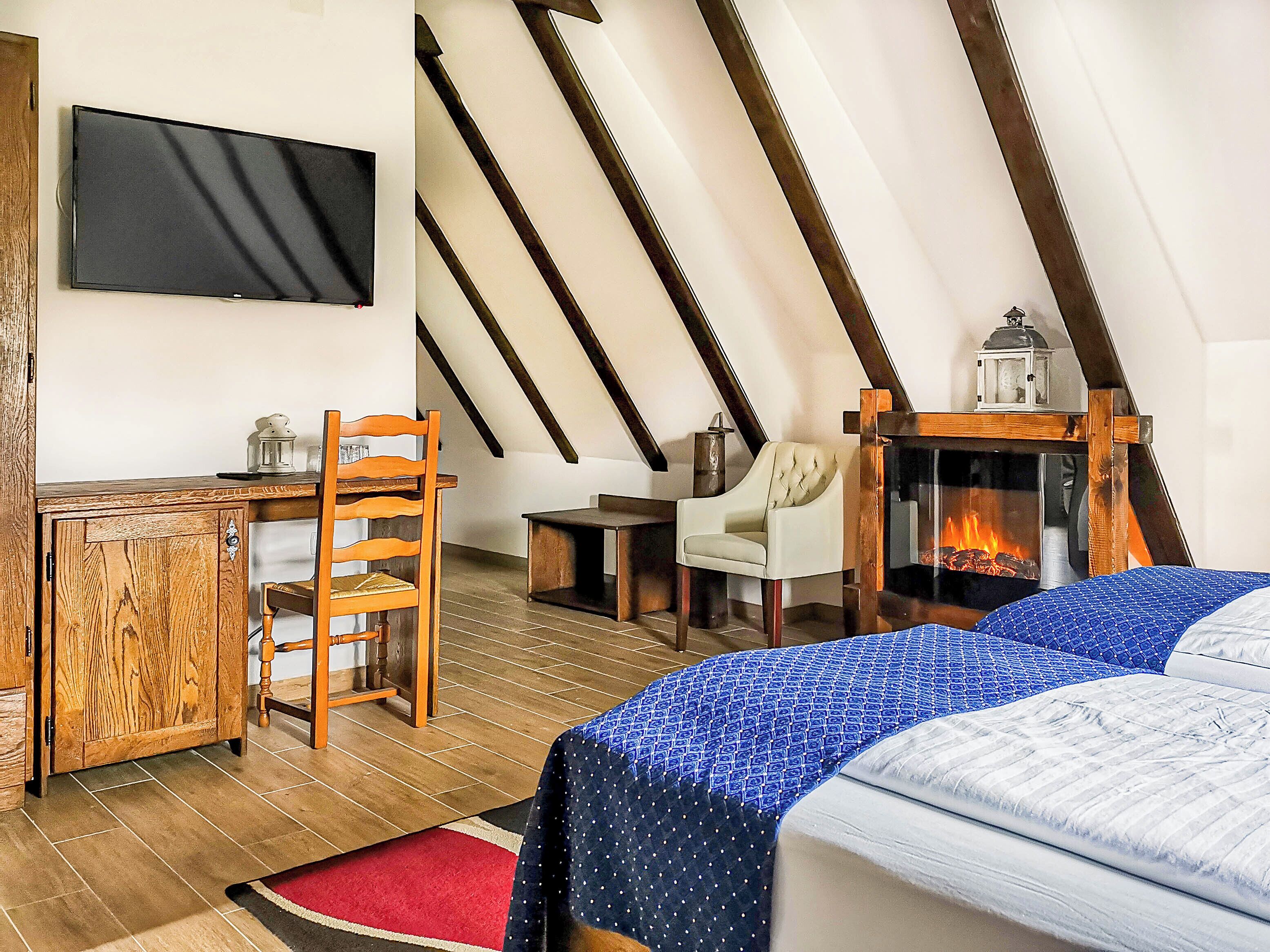 A cozy room with a bed, a desk, a chair, and a fireplace.