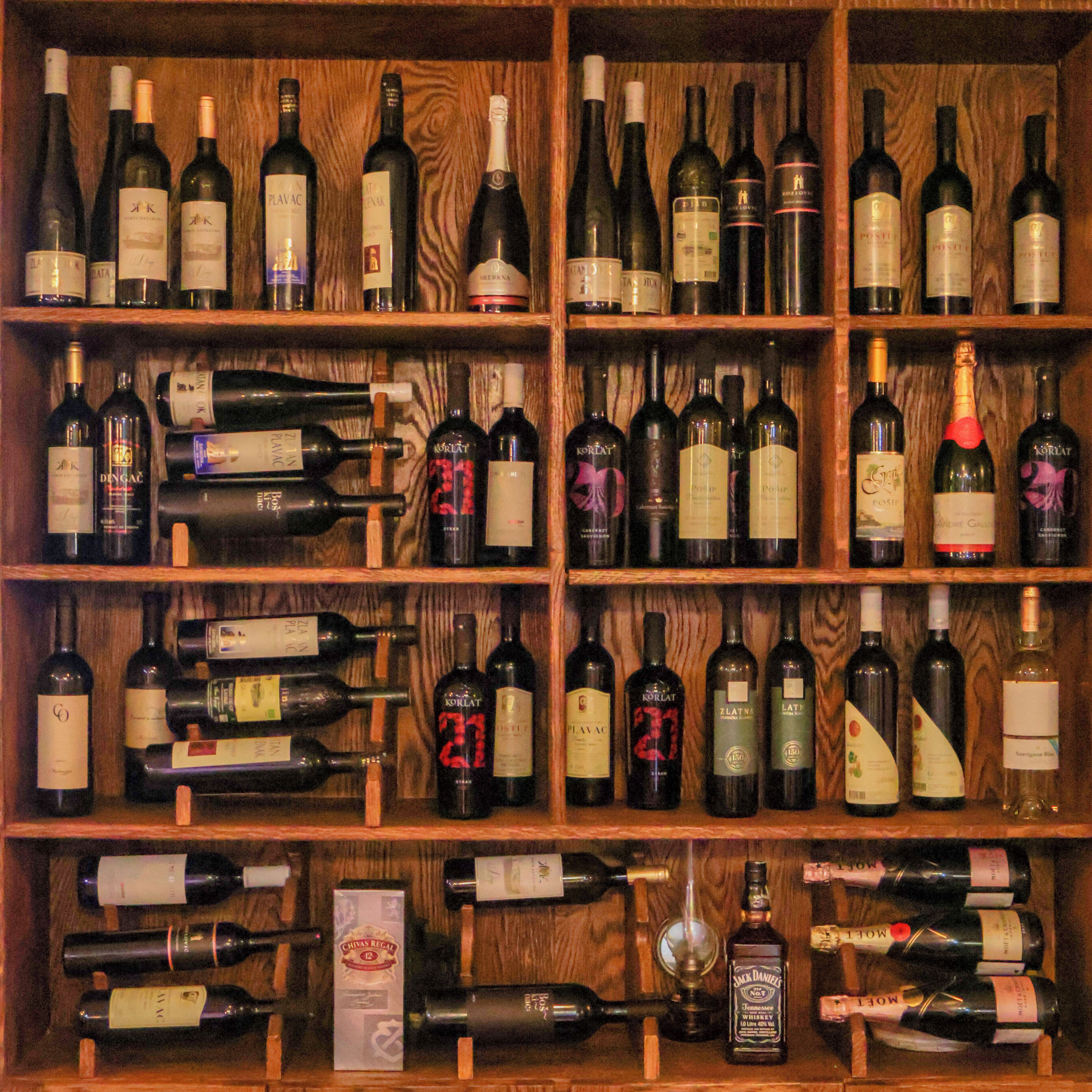 Una botellera de madera con varias repisas que sostienen diferentes botellas de vino.