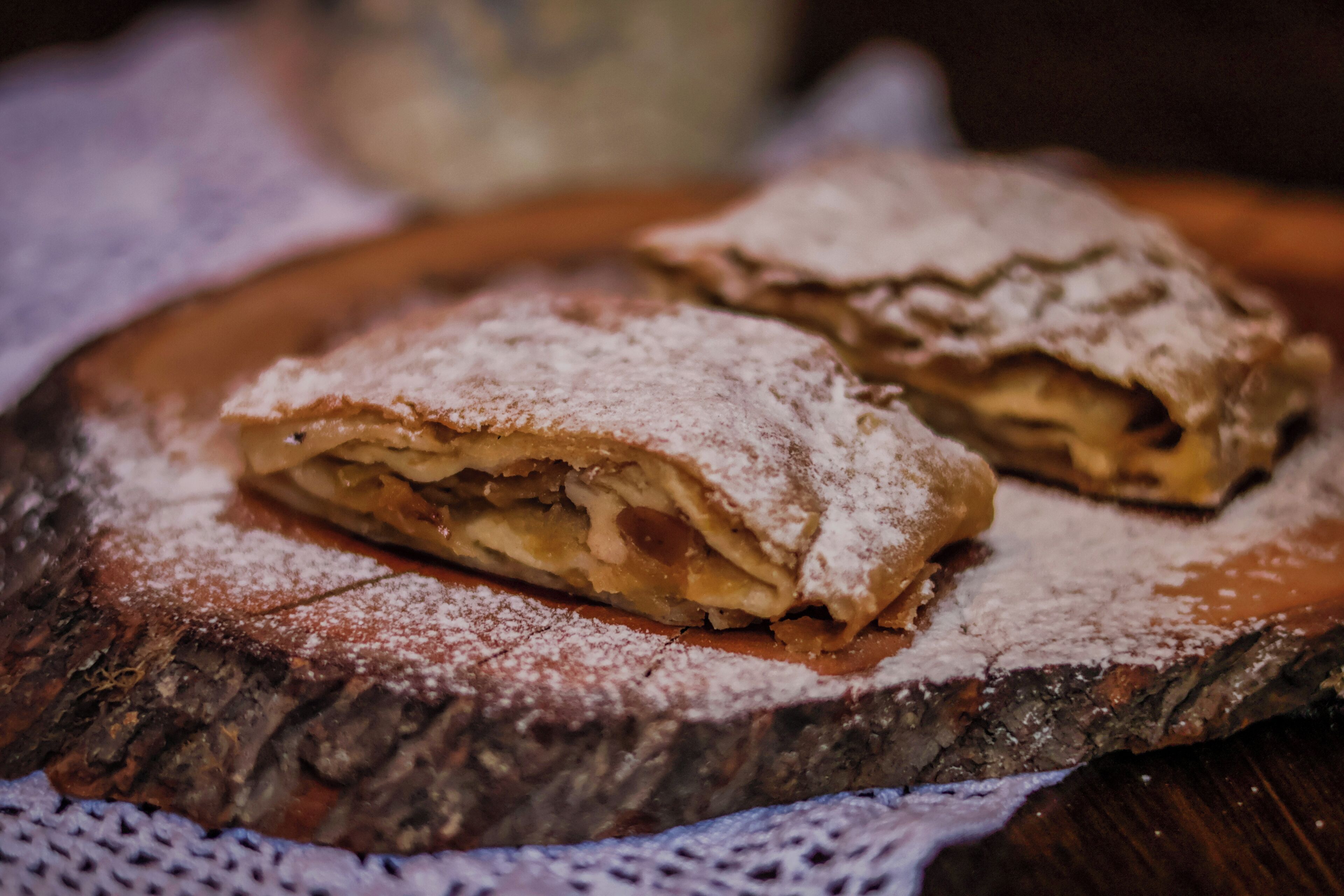 A pastry on a wooden board with a dusting of powdered sugar.