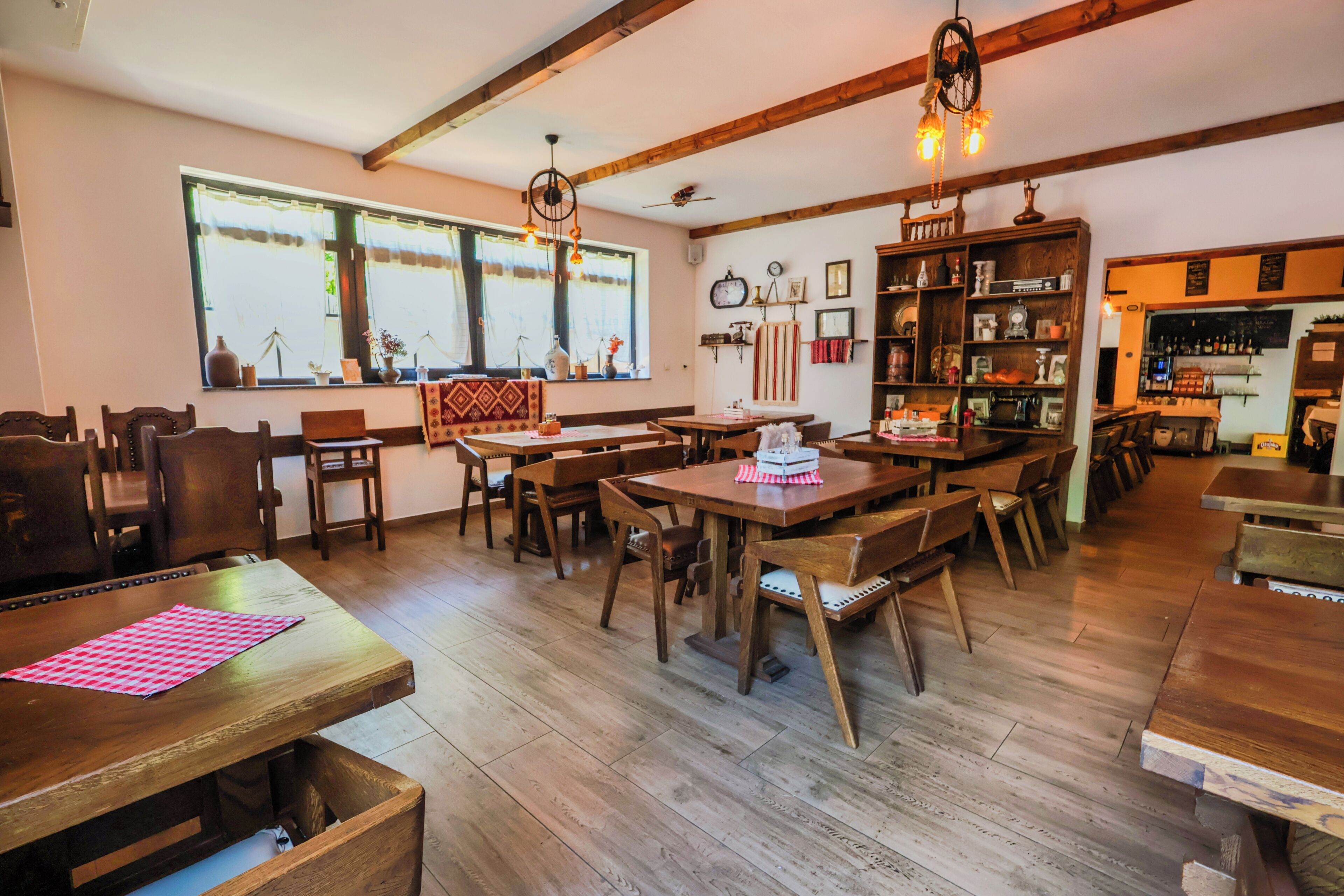 Een gezellig restaurant met houten meubels, een bar en grote ramen met gordijnen.