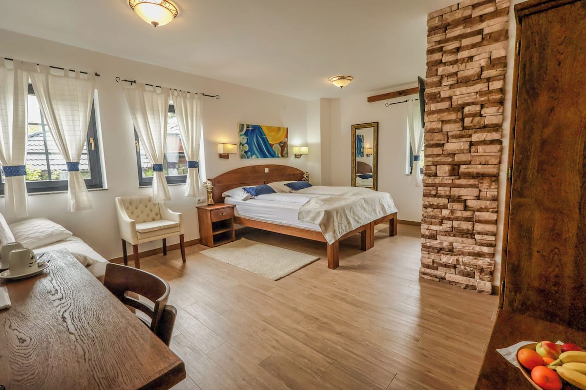A bedroom with a wooden bed, a nightstand, a chair, a table, and a fruit bowl.