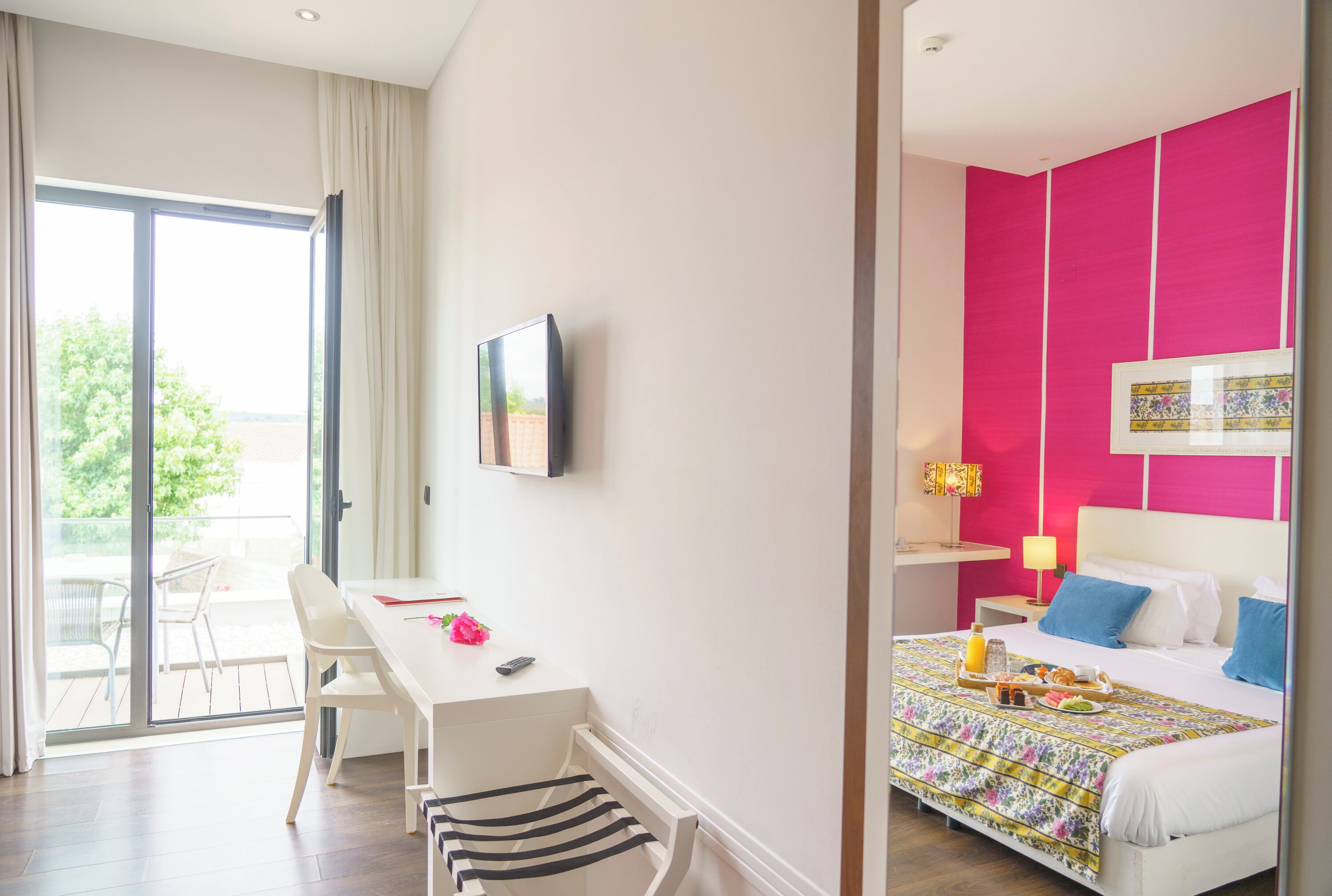 Una habitación de hotel con cama, escritorio, silla, ventana y balcón.