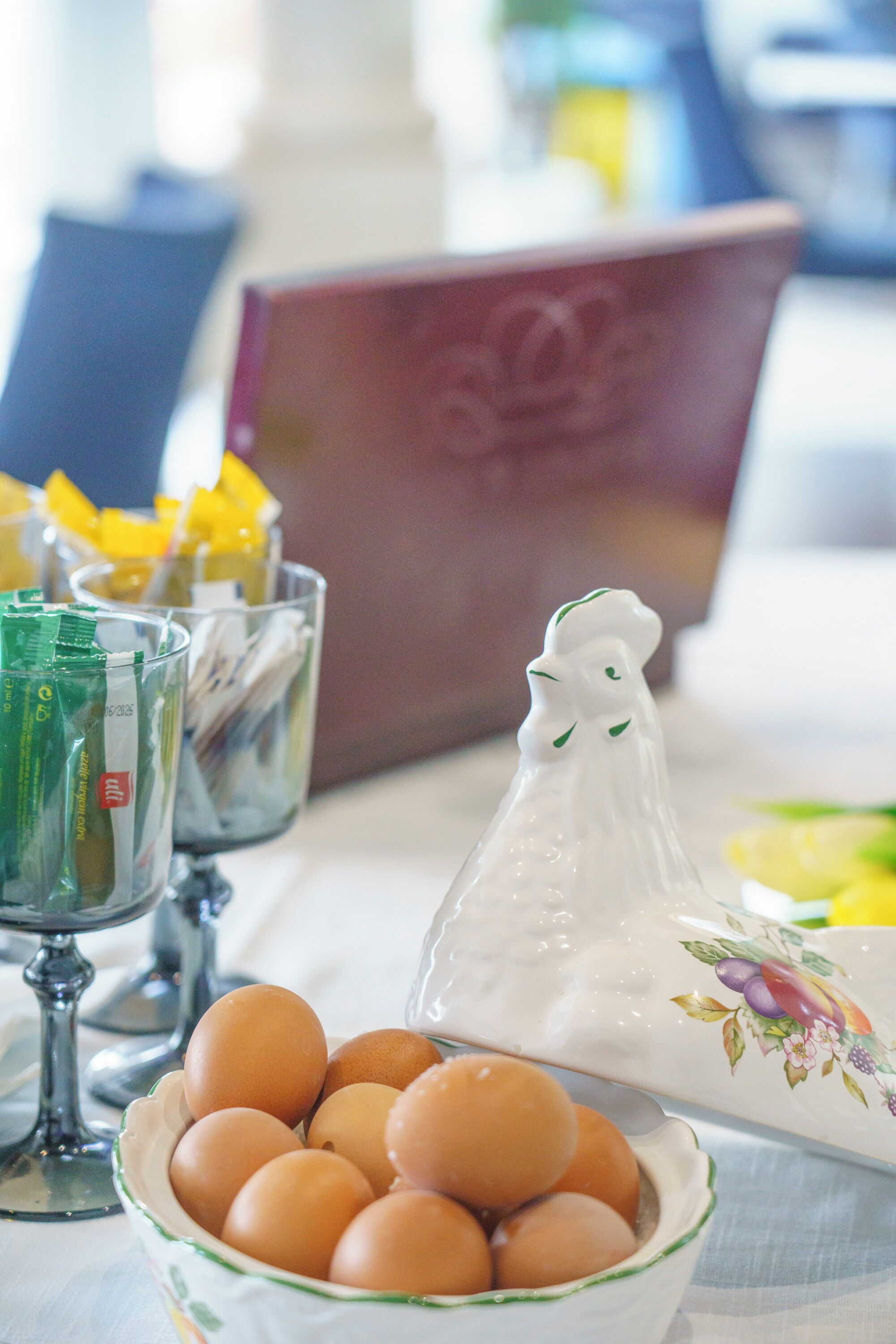 A table with a bowl of eggs, a salt shaker, and glasses with packets.