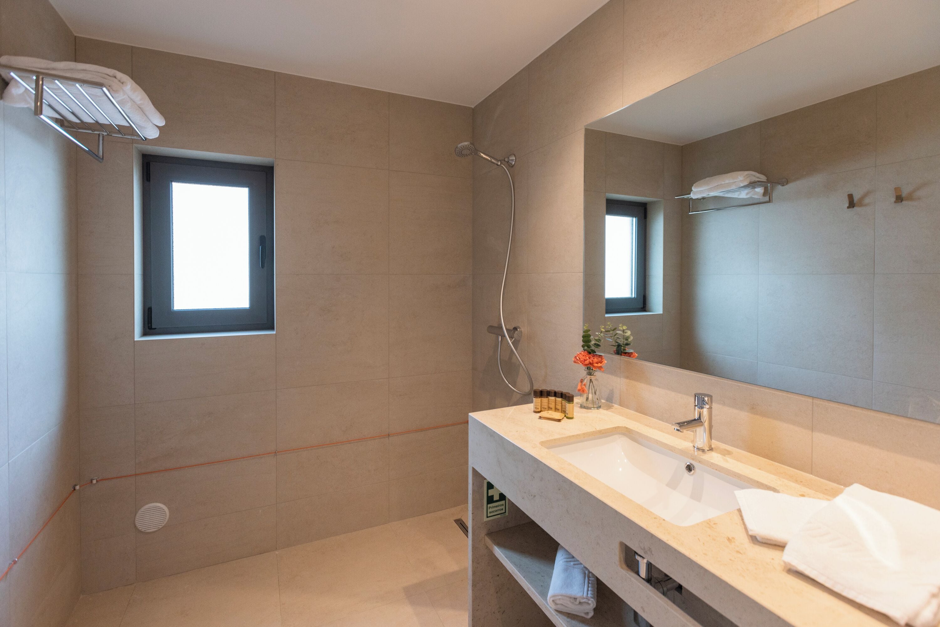 Une salle de bain moderne avec un grand miroir, une douche et un lavabo.