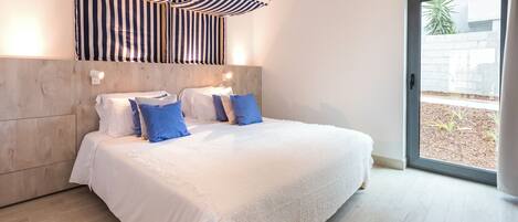 A bedroom with a large bed, a striped canopy, a wooden headboard, and a view of the outdoors through a glass door.