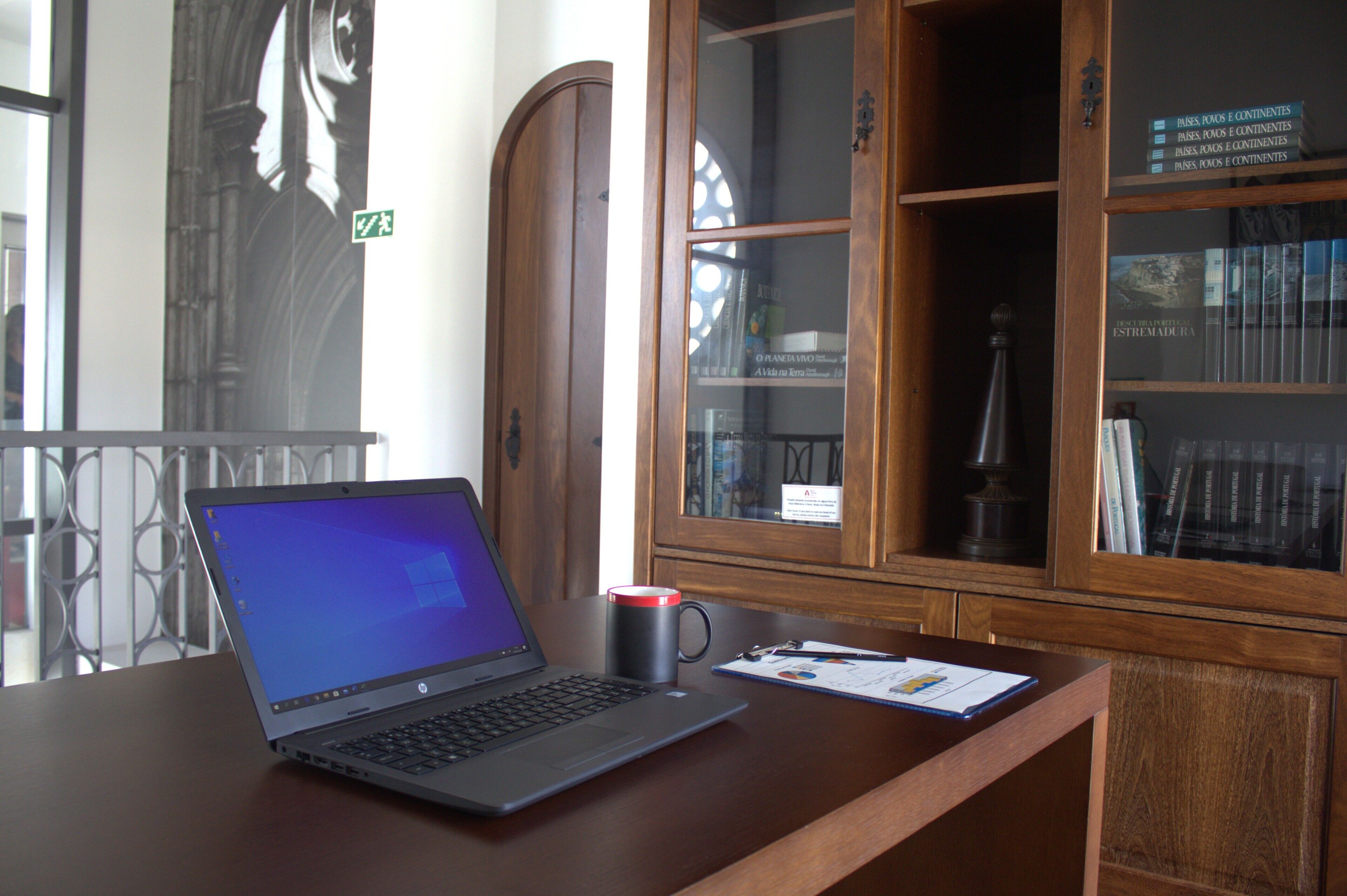 Un ordinateur portable sur un bureau, avec une tasse et un document.