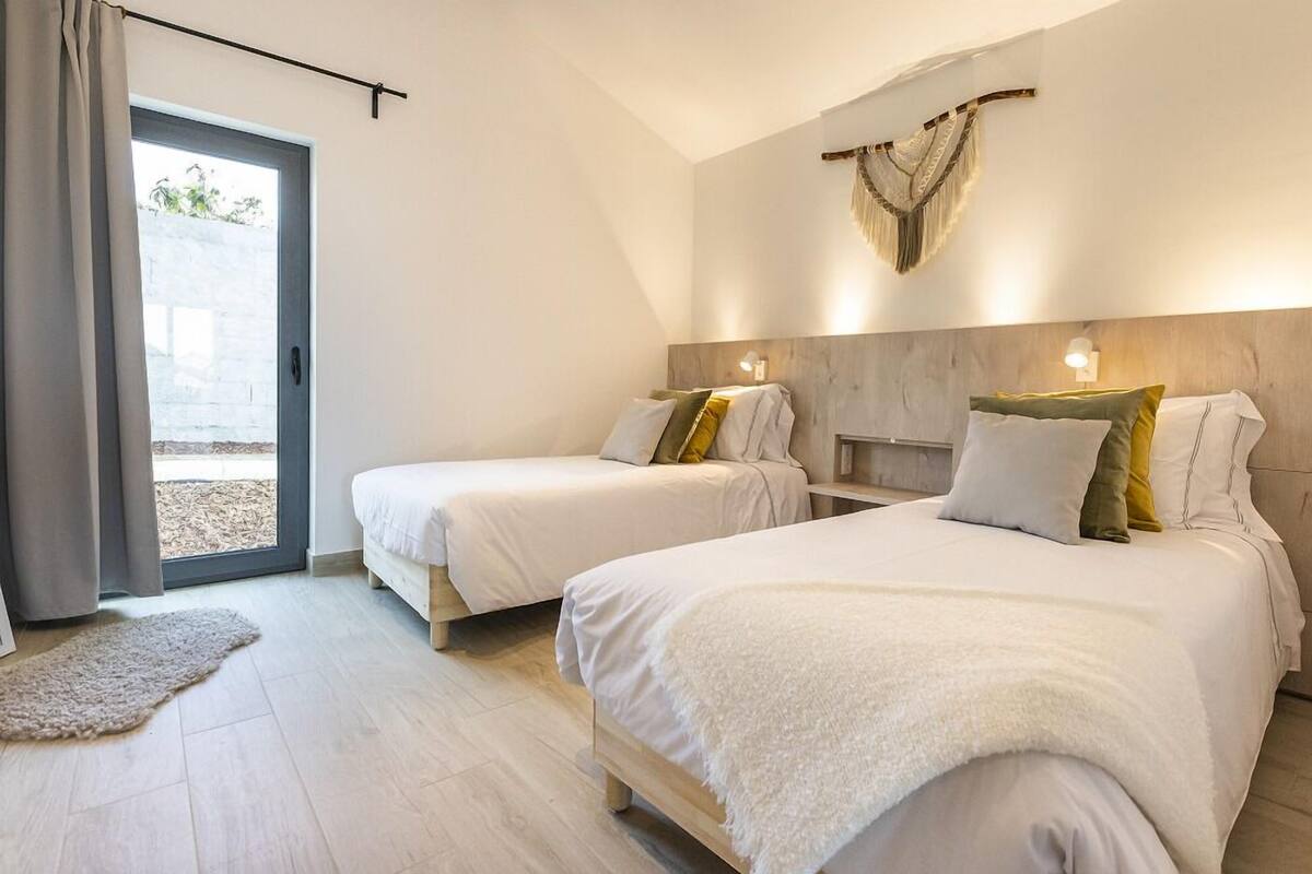 Un dormitorio moderno con dos camas, un ventanal y vistas al exterior.