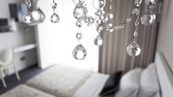 A bedroom with a bed, a bedside table, and a hanging chandelier with crystal decorations.