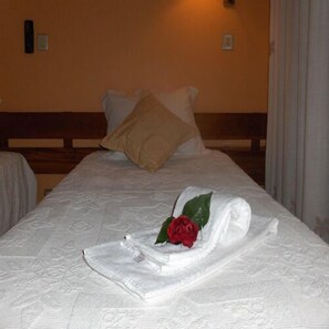 A neatly made bed with a white comforter, a red rose, and a folded towel. - São Roque 5179 AL (Portimão)