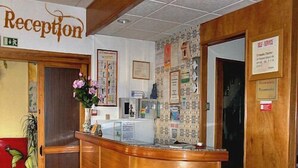 A reception area with a wooden counter, a reception desk, a wall-mounted clock, and a sign indicating the reception.