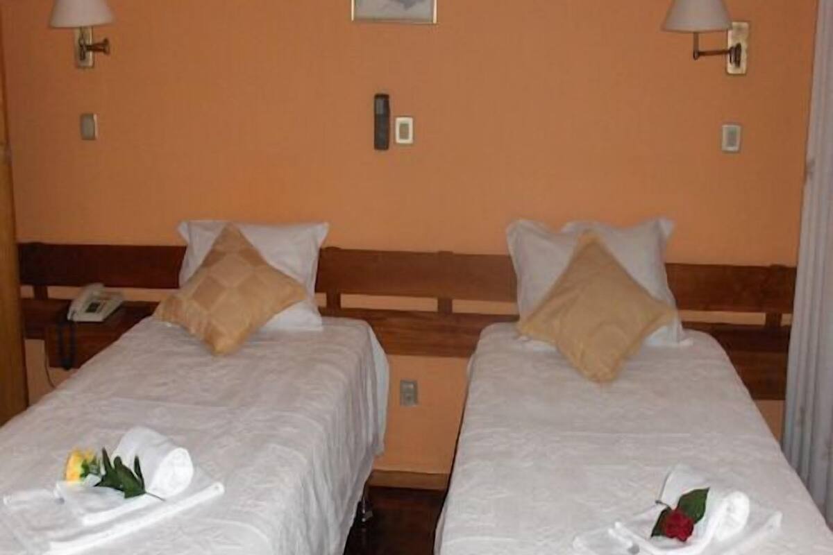 A hotel room with two beds, each with a pillow and a rolled towel.