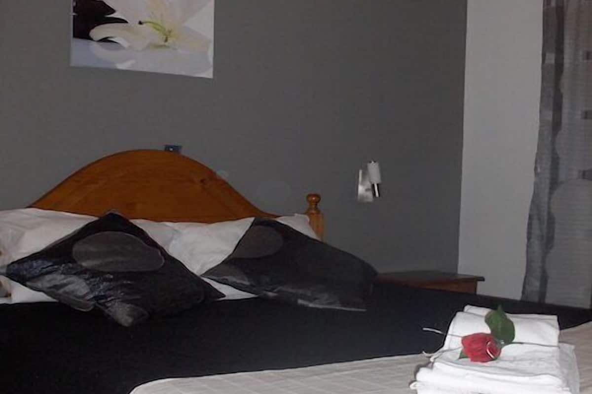 A hotel room with a bed, a nightstand, and a wall-mounted lamp.
