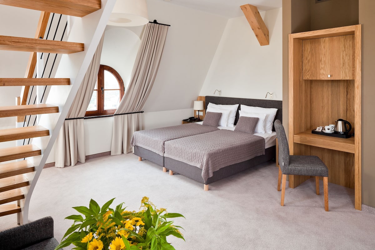 A modern bedroom with a bed, a chair, a desk, and a staircase.