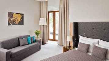 A hotel room with a bed, a sofa, a lamp, and a painting on the wall.