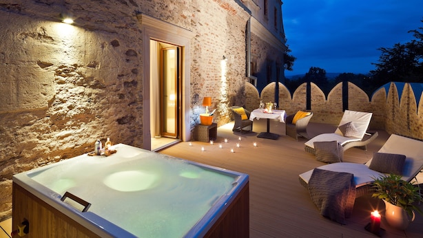 A spa area with a hot tub, seating, and a stone wall. - Uroczysko Siedmiu Stawów & Spa by L'Occitane (Niemcza)