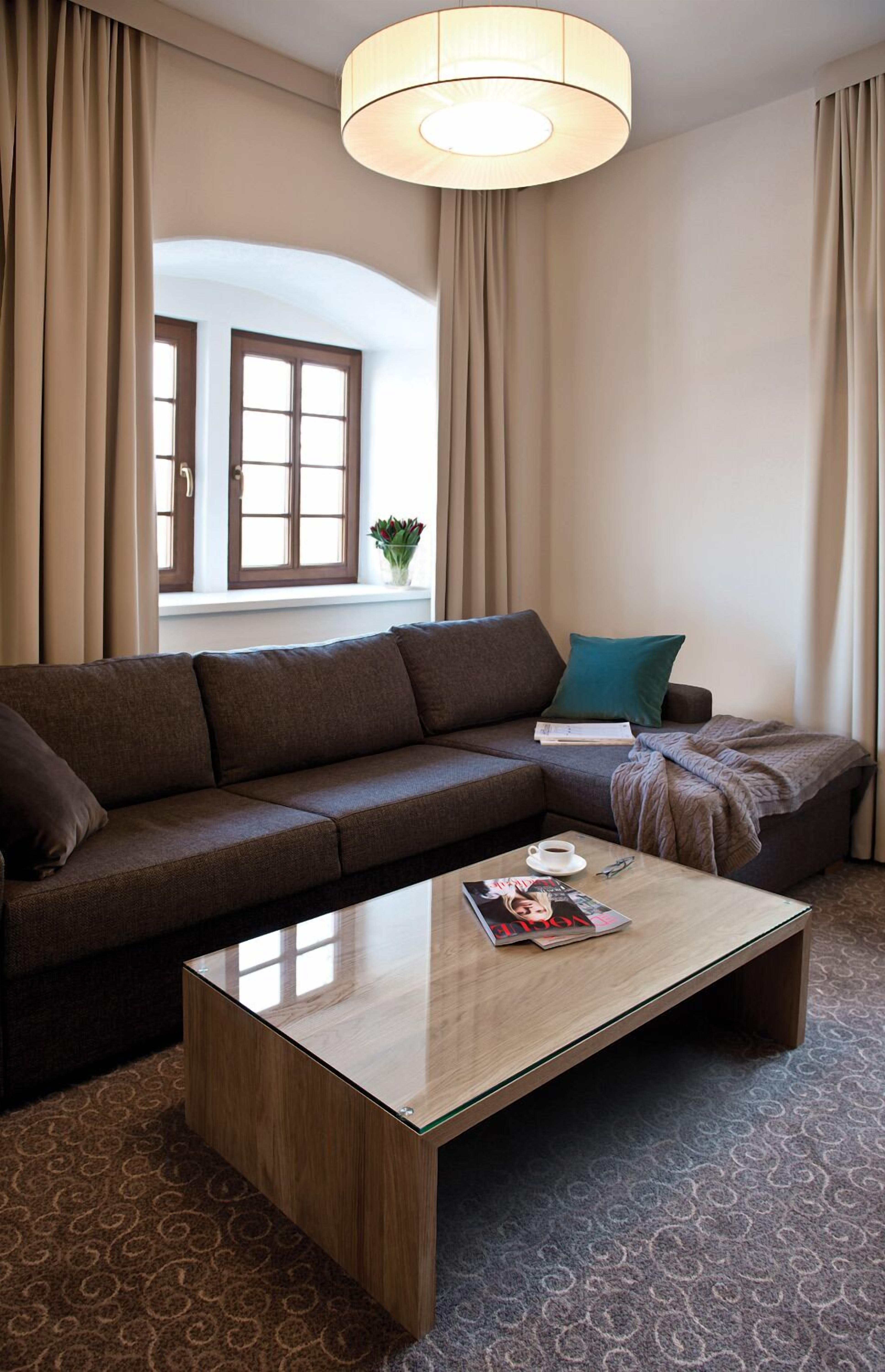 Ein modernes Wohnzimmer mit einer Couch, einem Couchtisch und einem Fenster mit Vorhängen.