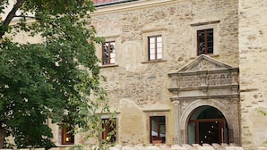 A stone building with a central entrance, multiple windows, and a tree in the foreground. - Uroczysko Siedmiu Stawów & Spa by L'Occitane (Niemcza)